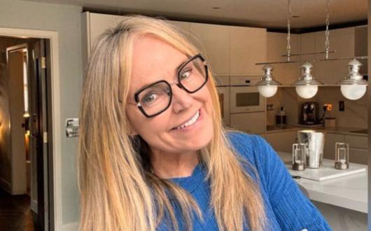 Woman smiling with blonde hair and glasses, her background is a modern kitchen