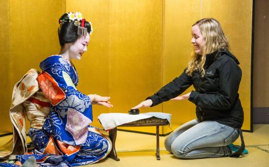 A woman and maiko sitting together smiling