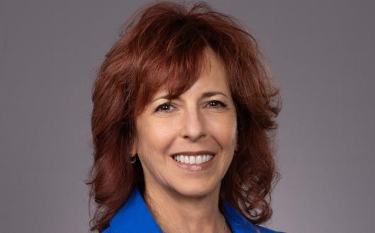 Professional headshot of smiling white woman with red hair