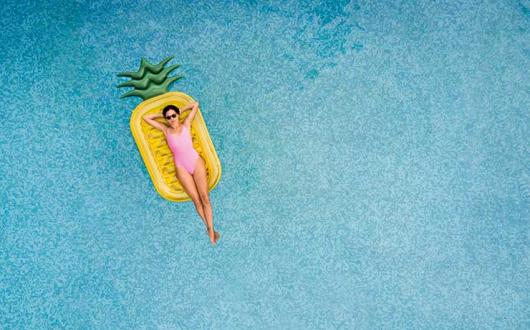 Woman floating on a pineapple lilo