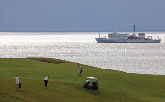 Playing golf on Cabot Links, Nova Scotia, with Akademik Ioffe in the background © Peter Ellegard-934