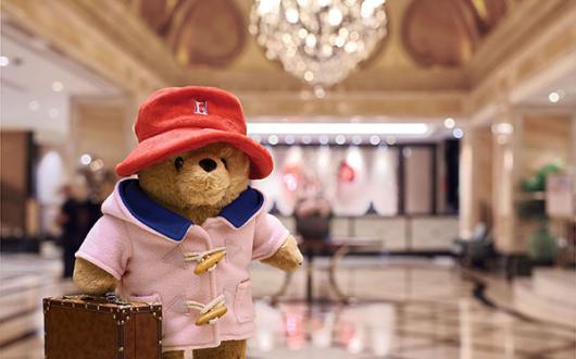 Paddington has swapped his traditional blue duffle coat for a new Langham-pink version