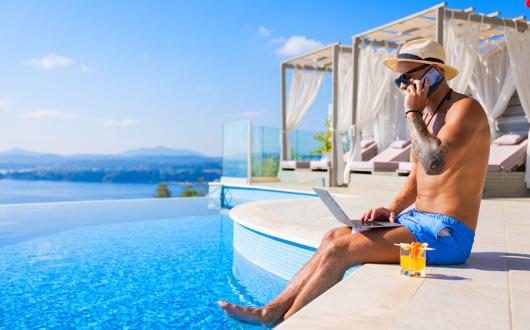 Holidaymaker using laptop by pool