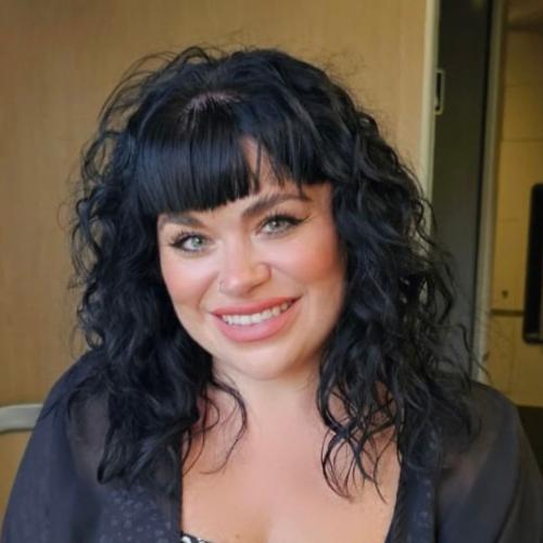 White woman with black curly hair smiling 