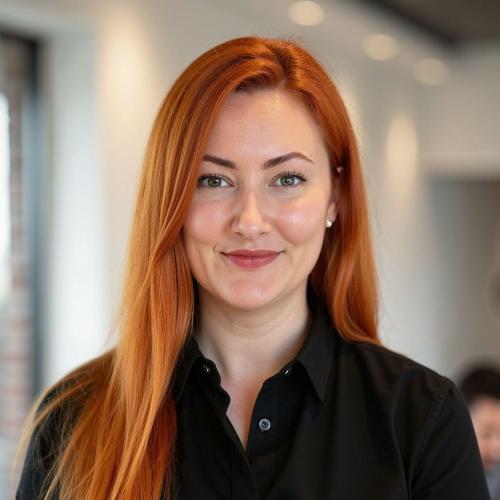 White woman with long, straight red hair and black shirt smiling at camera