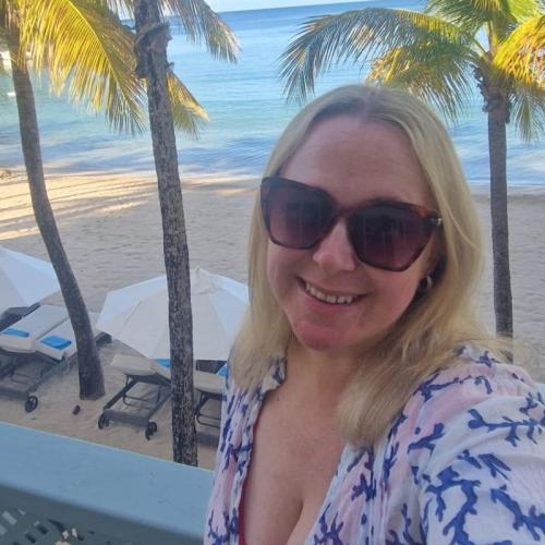 Blonde woman with sunglasses smiling in tropical location   