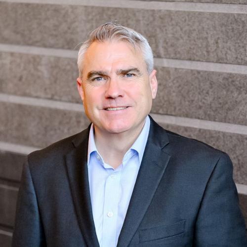 Man with grey hair and suit smiling 