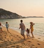 A family of five frolic happily on a sunny beach