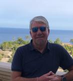 White man smiling in front of sea background