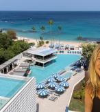 Woman smiling in front of picture of resort with pools 