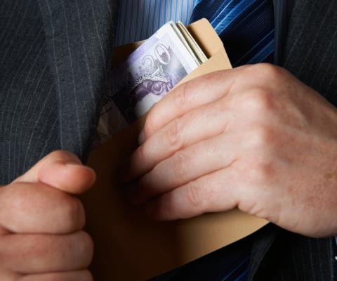 A man places a roll of bank notes in his jacket pocket