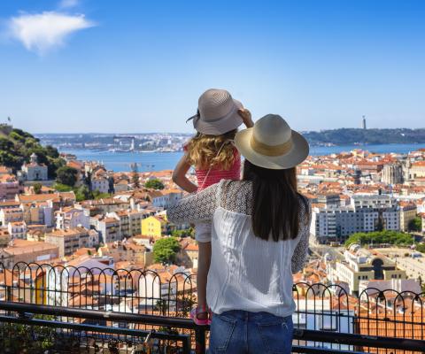 A mother with her daughter overlooking Portugal's capital Lisbon from a balcony