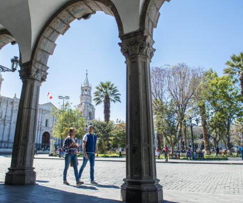 Two people walk through historic central square of Arequipa