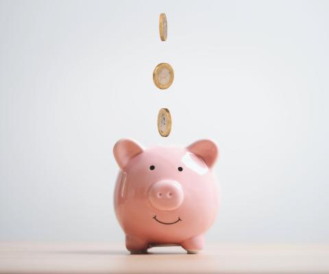Coins falling into a piggy bank