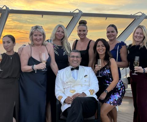 Travel agents stand behind MSC Yacht Club director with sunset in background