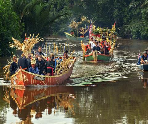 Sarawak locals in two boats moving down a brown river for a festival