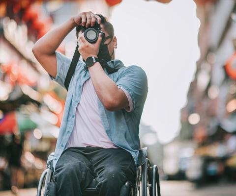 A wheelchair user takes a picture while travelling in an Asian city