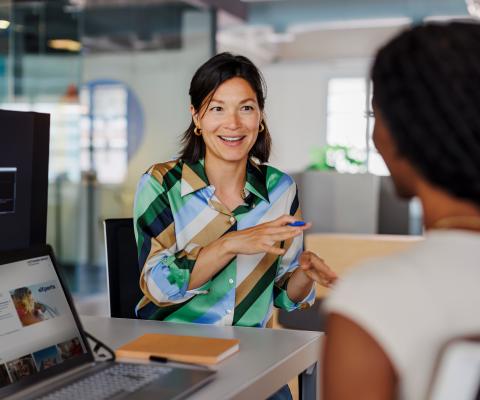 Two women sitting in office environment with laptops open