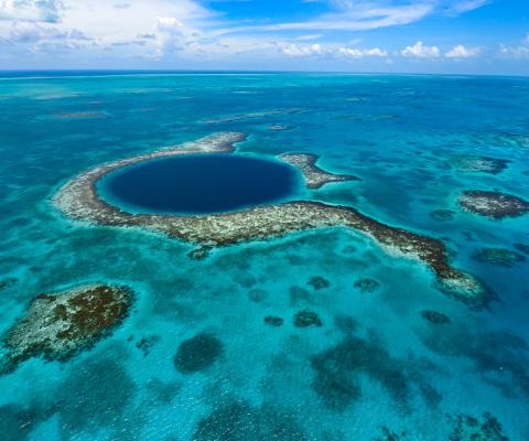 View of Belize Blue Hole from above, a dark blue circle in the middle of clear ocean