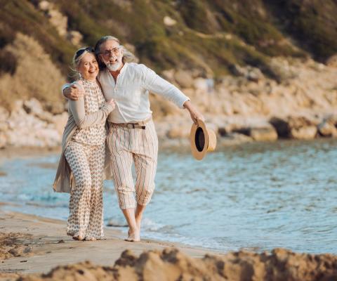 An older couple walk along the beach on holiday