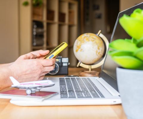 Person using a phone sitting at a laptop