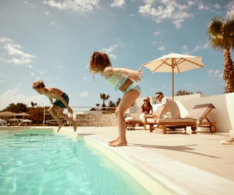 Two children mid-air jumping into a swimming pool 
