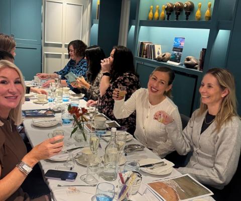Women sitting at table smiling and drinking