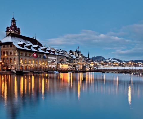 View of Lucerne at dusk with buildings lit up and snow on rooftops