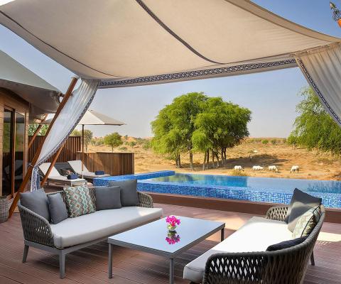 Sofa and chairs on a wooden patio with small pool and desert in background