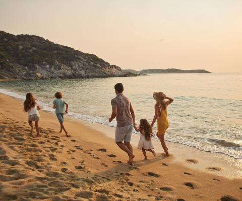 A family of five frolic happily on a sunny beach