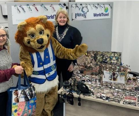 Team at Travel World Jersey next to Lions Club of Jersey mascot and collected glasses