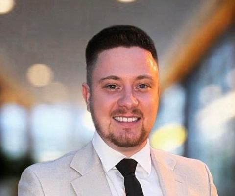 Man with brown hair and beard smiling at camera 