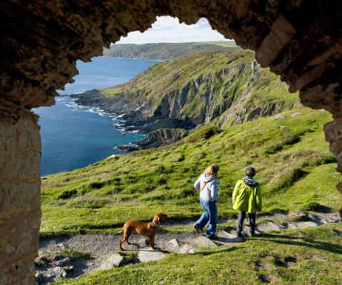 Couple with dog walking in the British coastal countryside