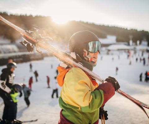 A skier with their skies over their shoulder