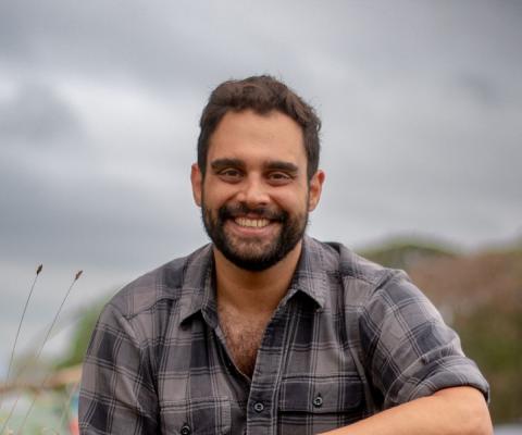 Man smiling in tartan shirt with mountain background 