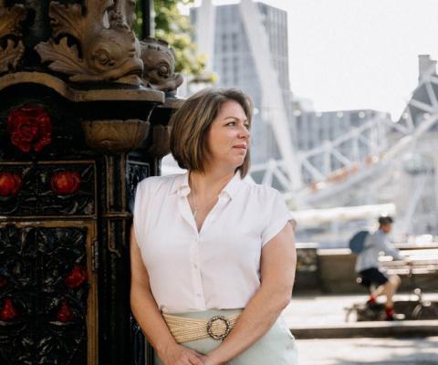 Brown haired woman outdoors in London, wearing white top and looking to the side