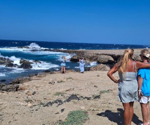 Two blonde women facing rugged coastline 