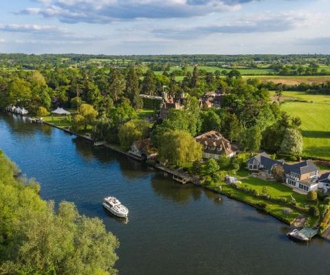 Aerial photograph of a boat on a river surrounded by trees and green fields