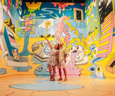 People looking around a room covered with walls covered in artwork