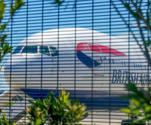 A grounded British Airways aircraft seen through a mesh fence