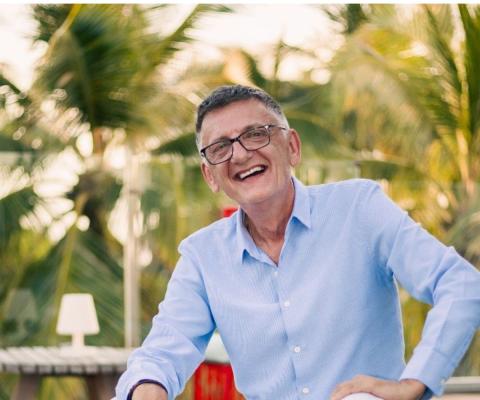 White man smiling with outdoors green background