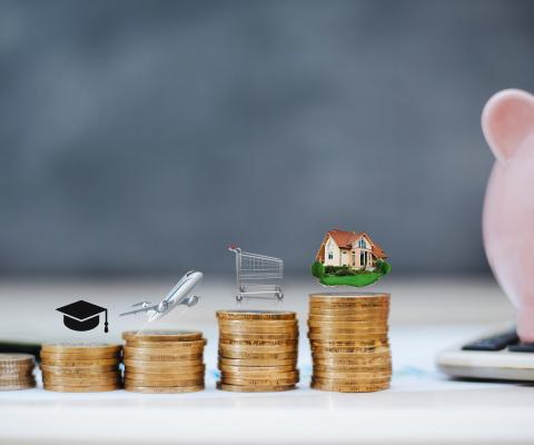 A row of coins of different heights with different spending priorities on top of them next to a piggybank