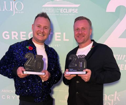 Two men holding trophies and smiling 