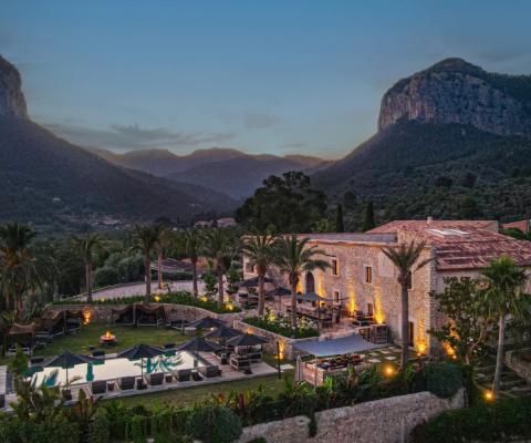 Aerial shot of luxurious chateau with lush gardens and rugged moutaineous background 