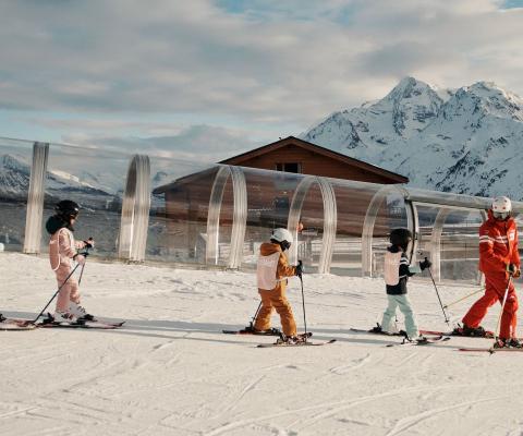 children on skis following an instructor