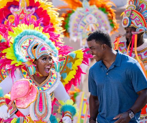 Woman wearing elaborate and colourful costume and local tourist smiling at each other