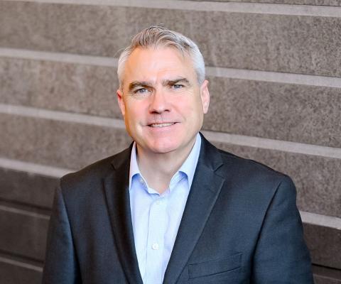 Man with grey hair and suit smiling 