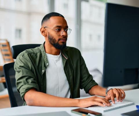 A young professional types at their office workstation