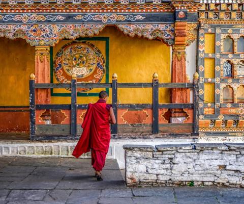 Bhutanese man in traditional clothing outside yellow temple