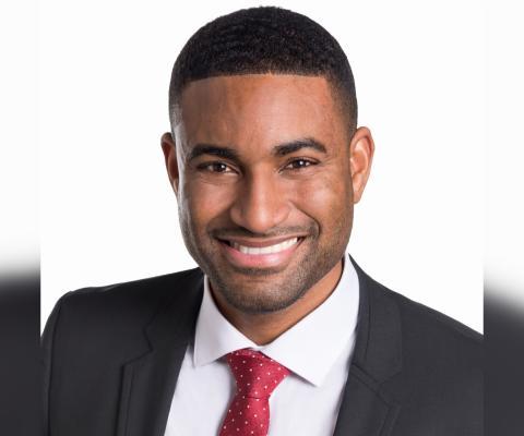 Professional headshot of Black man wearing suit and smiling 